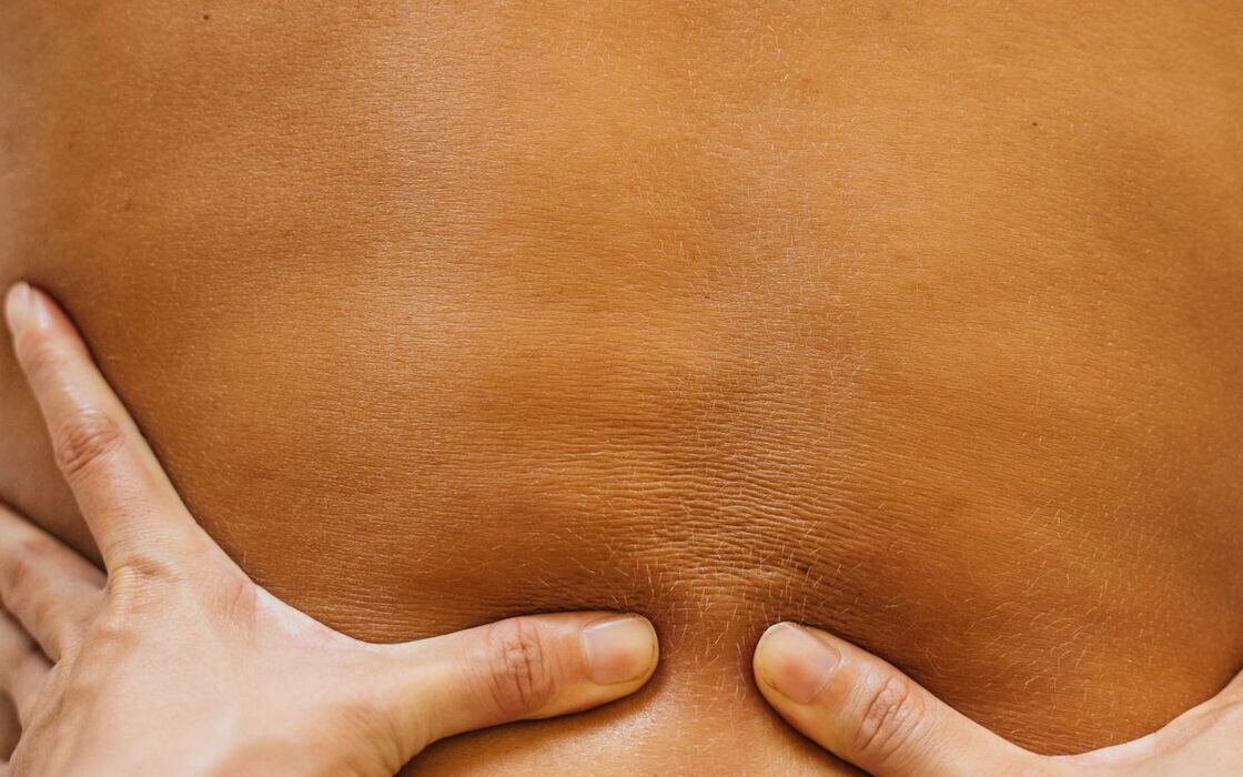 Deep tissue massage — focused thumb pressure along the lower back